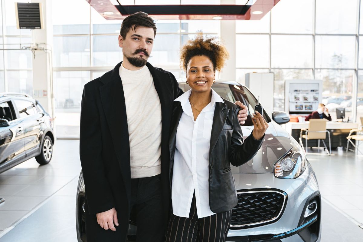 A couple receiving the keys to their new car at a dealership